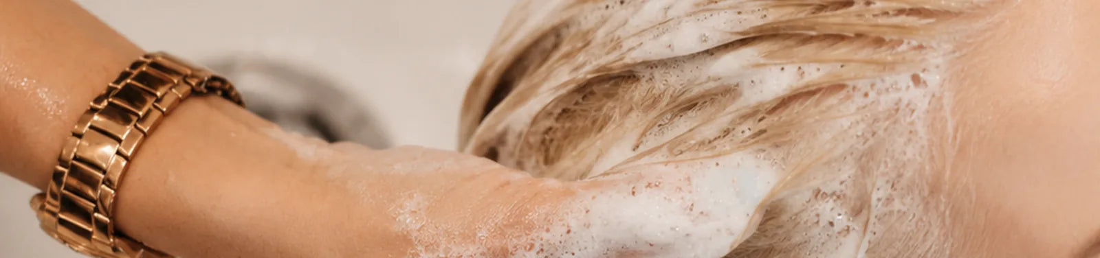 Hands washing hair at a salon basin